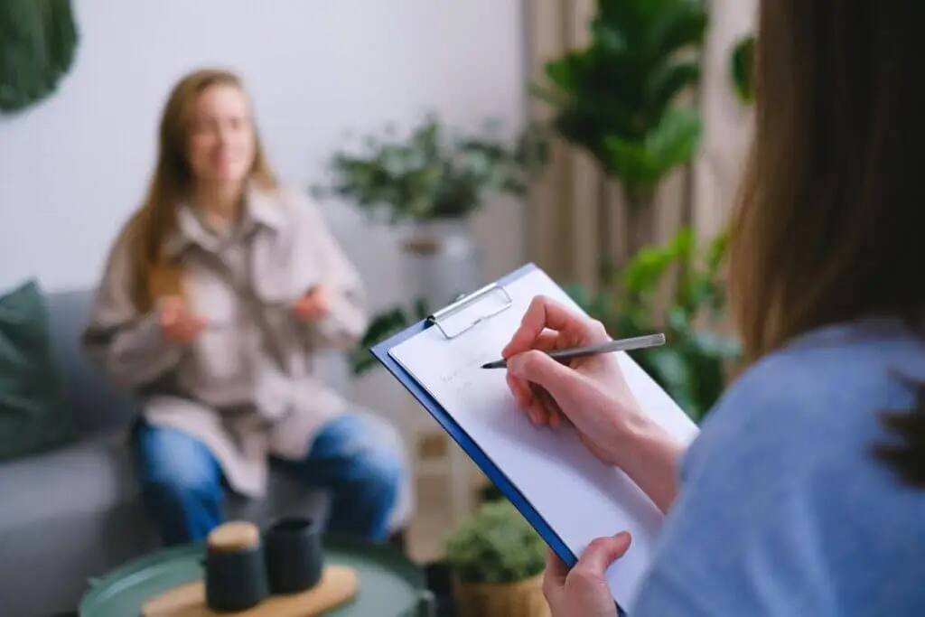 Therapist taking notes on a clipboard during a therapy session
